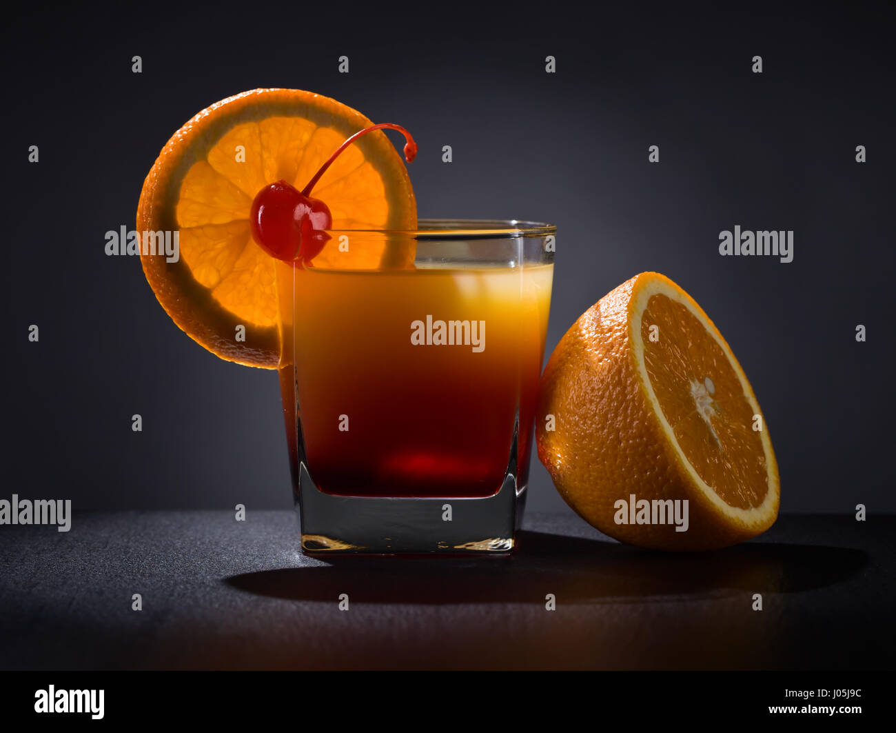 Cocktail "Tequila Sunrise" garniert mit Orangenscheibe und süßen Kirschen. Gold Tequila