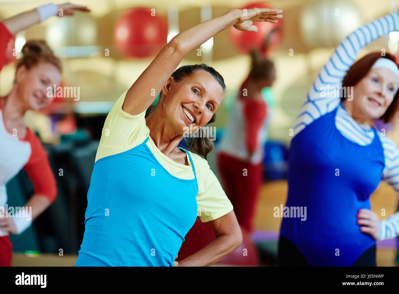 Reife energische Frauen streckte ihre Arme während des Trainings Stockfoto