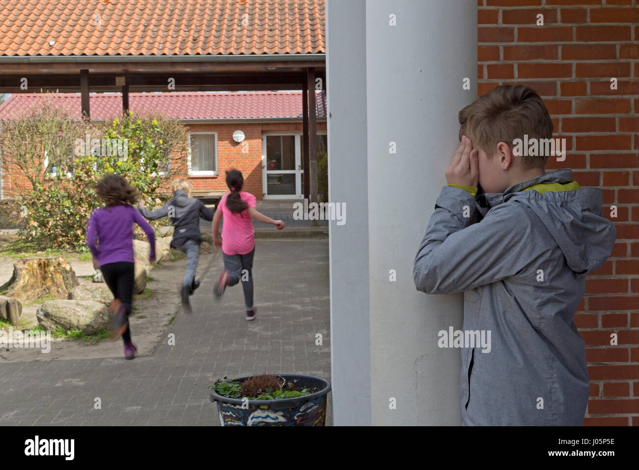 Schülerinnen und Schüler an der Grundschule spielen verstecken und suchen in Pause, Niedersachsen, Deutschland Stockfoto