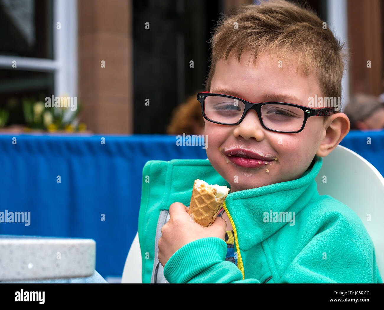 Junge lächelnd Eis essen Kegel mit glücklichen zufriedenen Ausdruck, Schottland, Großbritannien Stockfoto