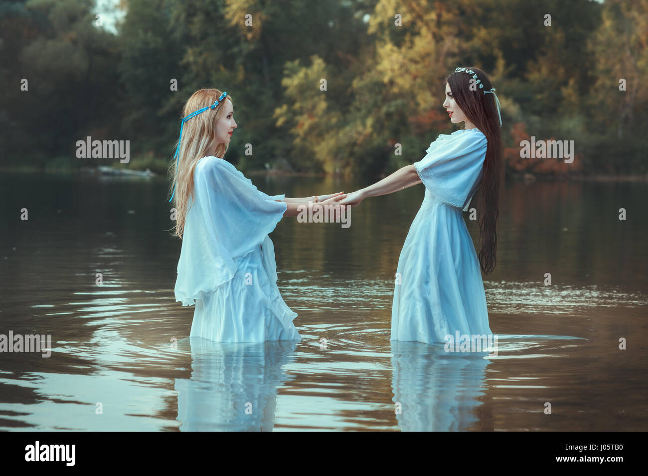 Zwei Frauen Hand in Hand, sie sind gekleidet in weißen Kleidern und im Wasser sind. Stockfoto
