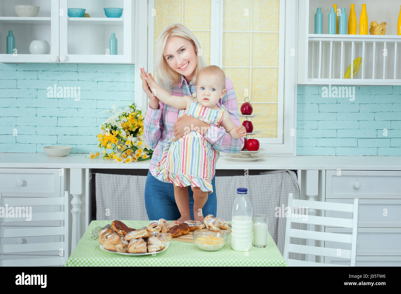 Mutter mit dem Kind in der Küche, auf einem Tisch liegt das vorbereitete fancy Brot. Stockfoto