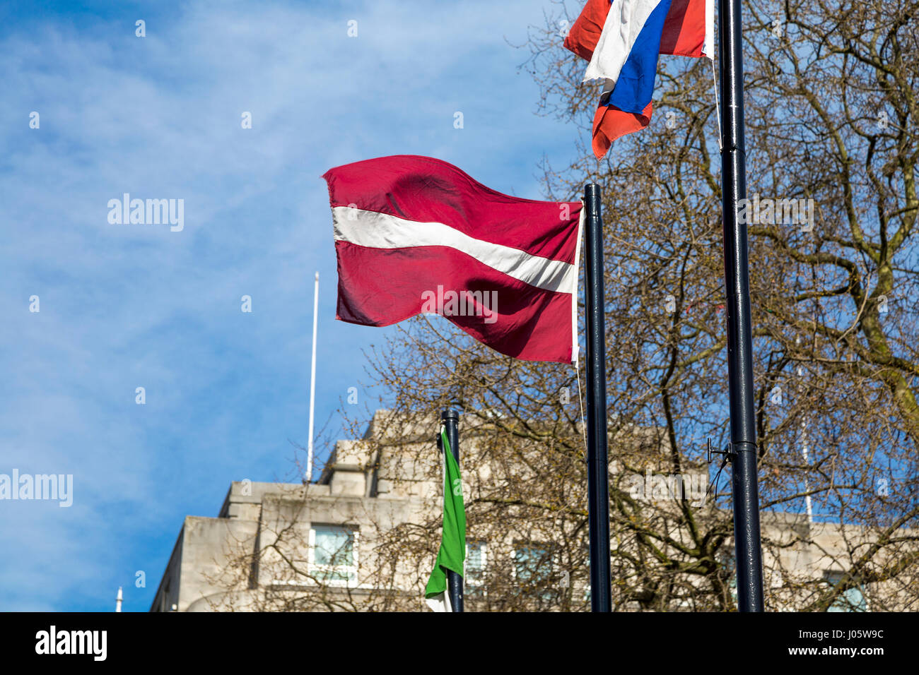 Lettische Fahne an einem Fahnenmast gegen blauen Himmel Stockfoto