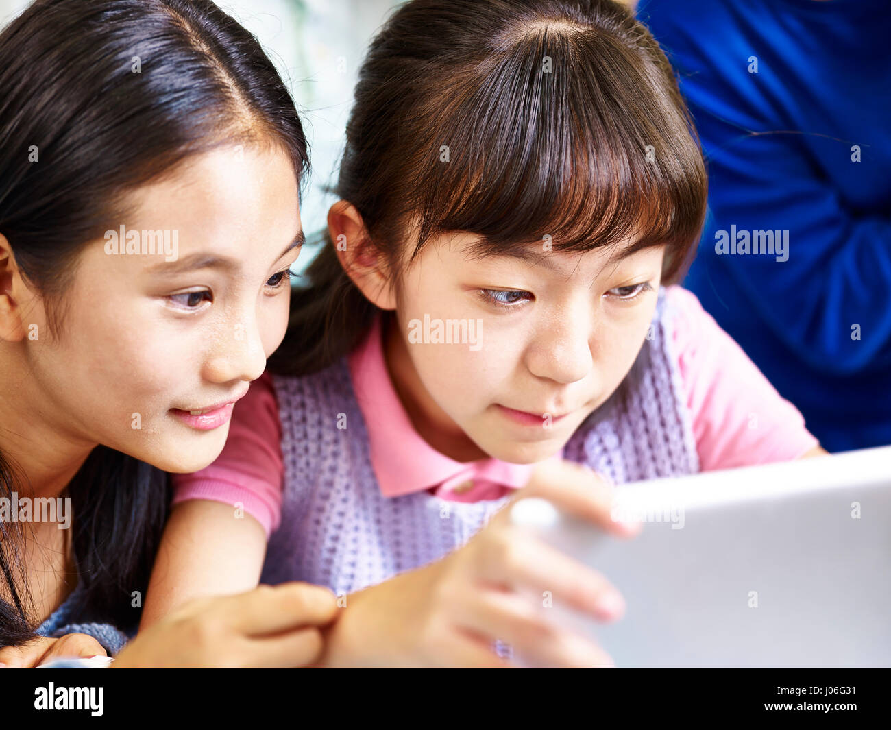 zwei asiatische Grundschüler mit digitalen tablet zusammen Stockfoto