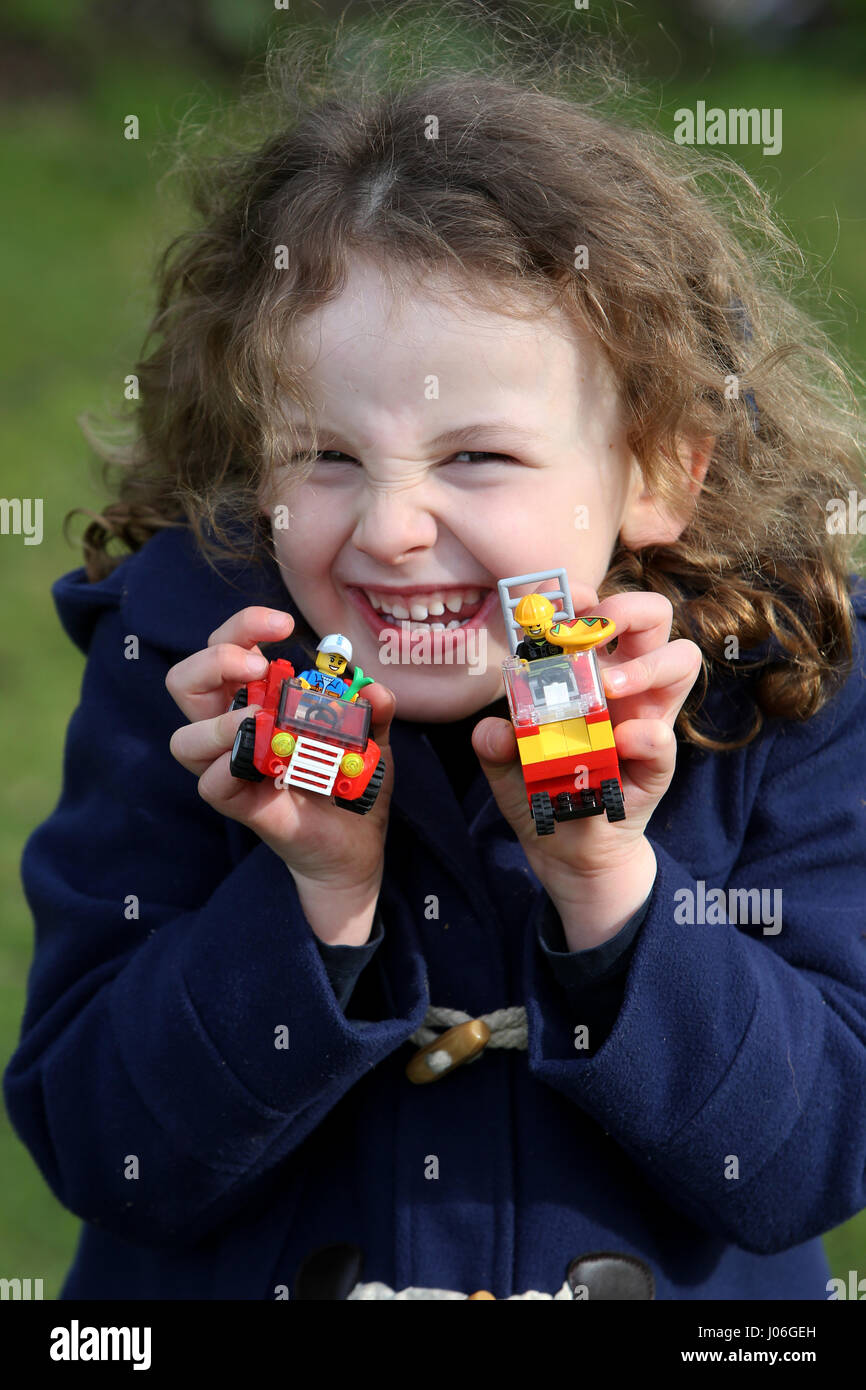 Ein junges Mädchen abgebildet draußen spielen mit Lego in einem Park in Chichester, West Sussex, UK. Stockfoto