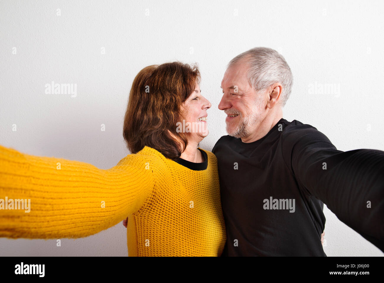 Älteres Paar in Liebe umarmt, wobei Selfie. Studio gedreht. Stockfoto