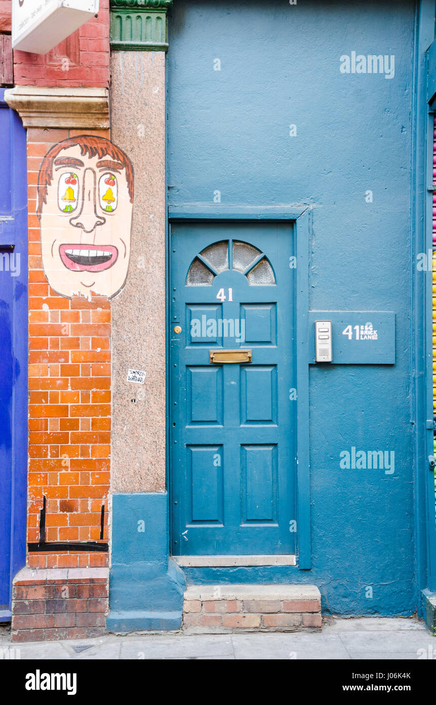 Nr. 41 Brick Lane im Osten Londons hat einen Kopf gemalt oberhalb und links von der Haustür. Stockfoto