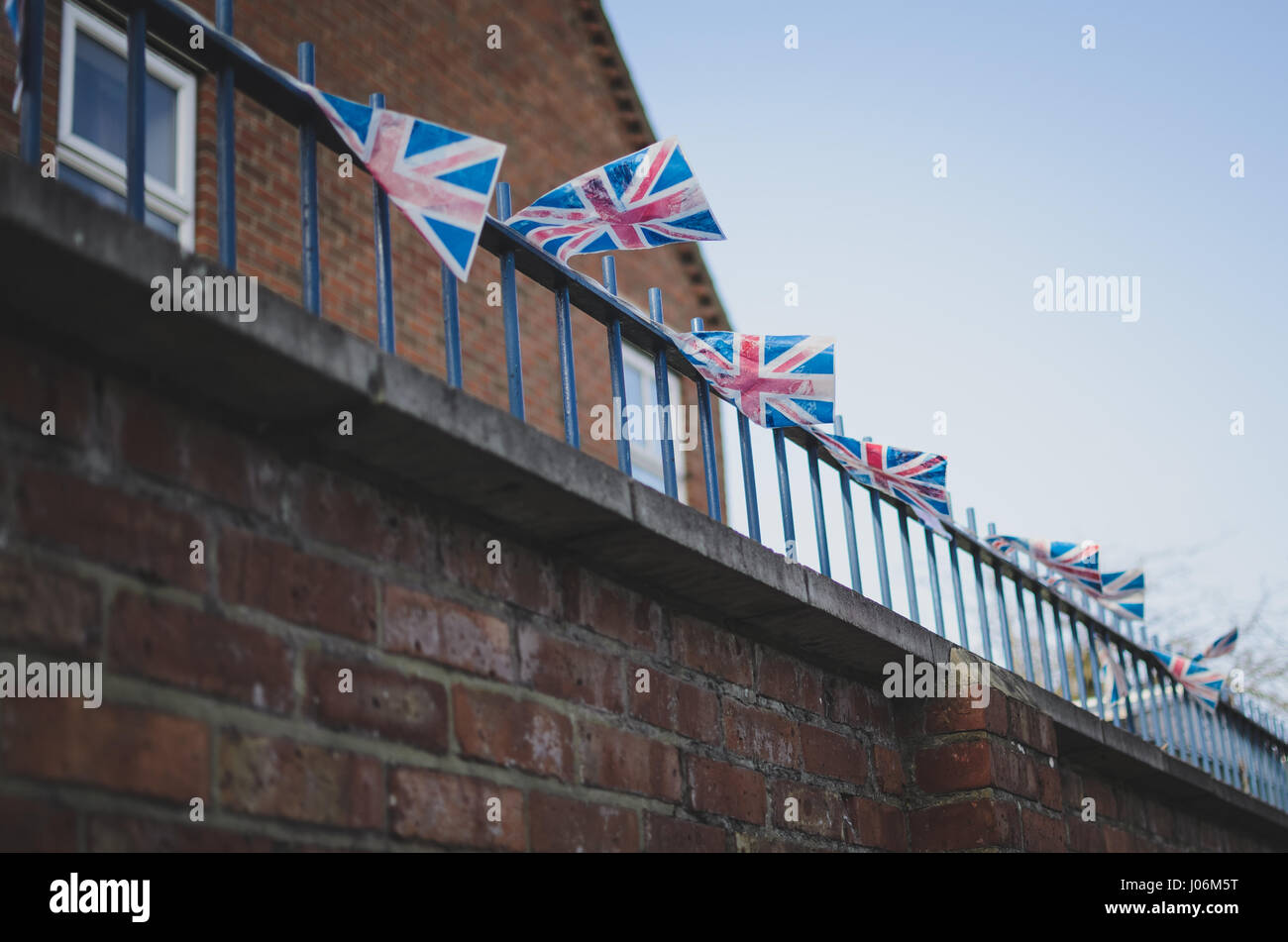 kleine Union Jack Flagge auf einem Balkon in windigen Kälte. typisch britische rote Backsteingebäude im Hintergrund Stockfoto