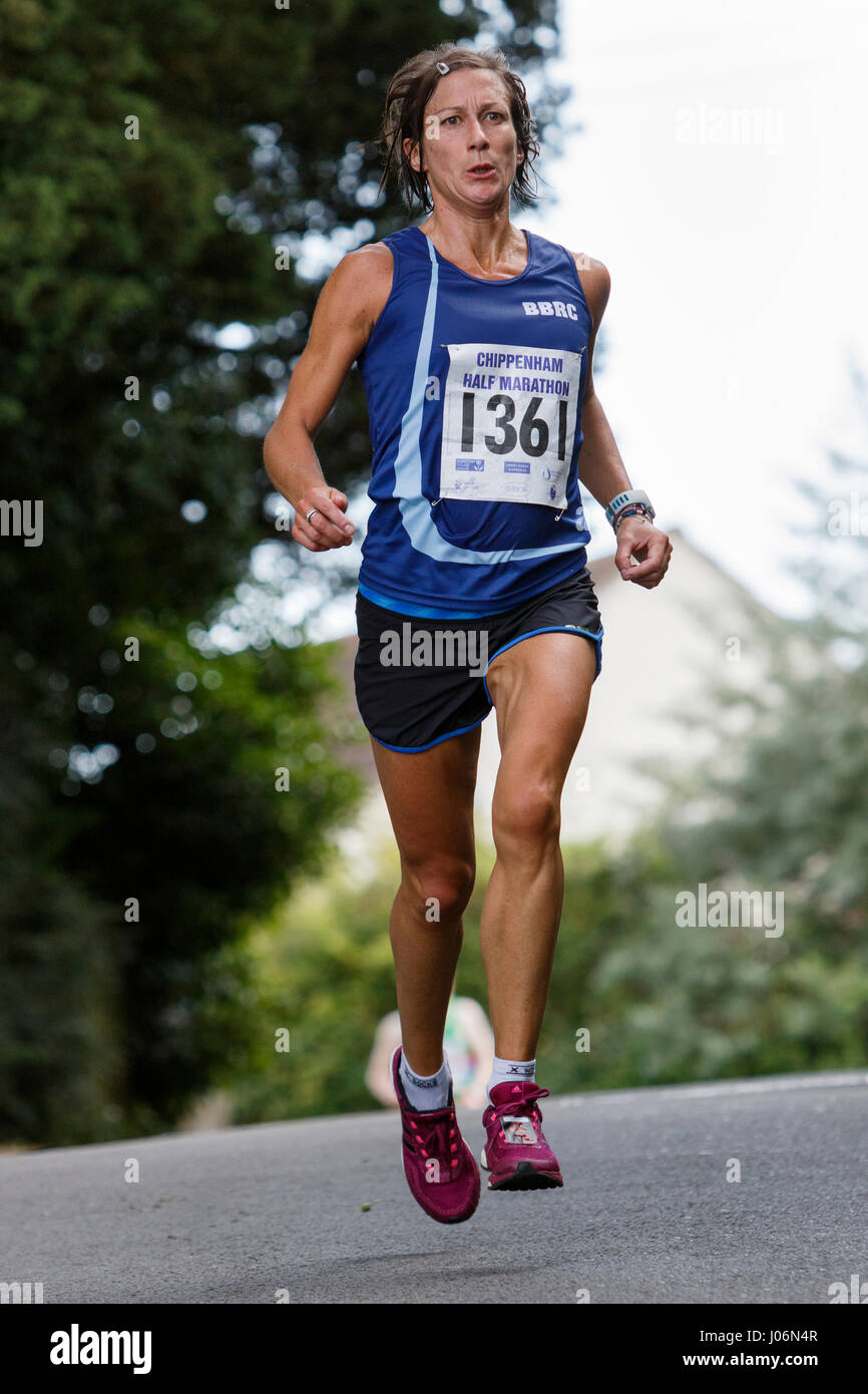 Eine junge Frau / Frau Athleten laufenden Sportbekleidung tragen abgebildet ist, läuft in einem Halbmarathon-Straßenrennen in Chippenham, England, UK Stockfoto