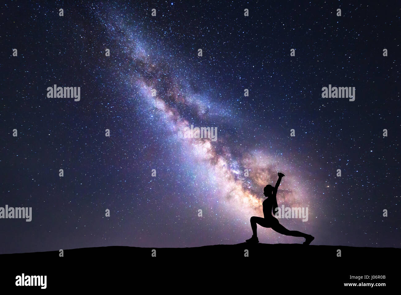 Milky Way mit Silhouette einer stehenden Frau praktizieren Yoga am Berg. Wunderschöne Landschaft mit Meditierenden Mädchen gegen sternenklaren Nachthimmel Stockfoto