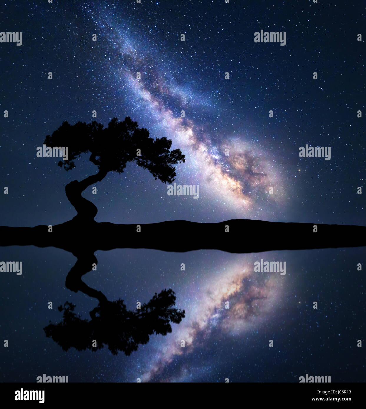 Milky Way mit allein krummen Baum auf dem Hügel in der Nähe des Flusses mit Himmel Spiegelung im Wasser. Bunte Nacht-Landschaft mit Milky Way, Sternenhimmel Stockfoto