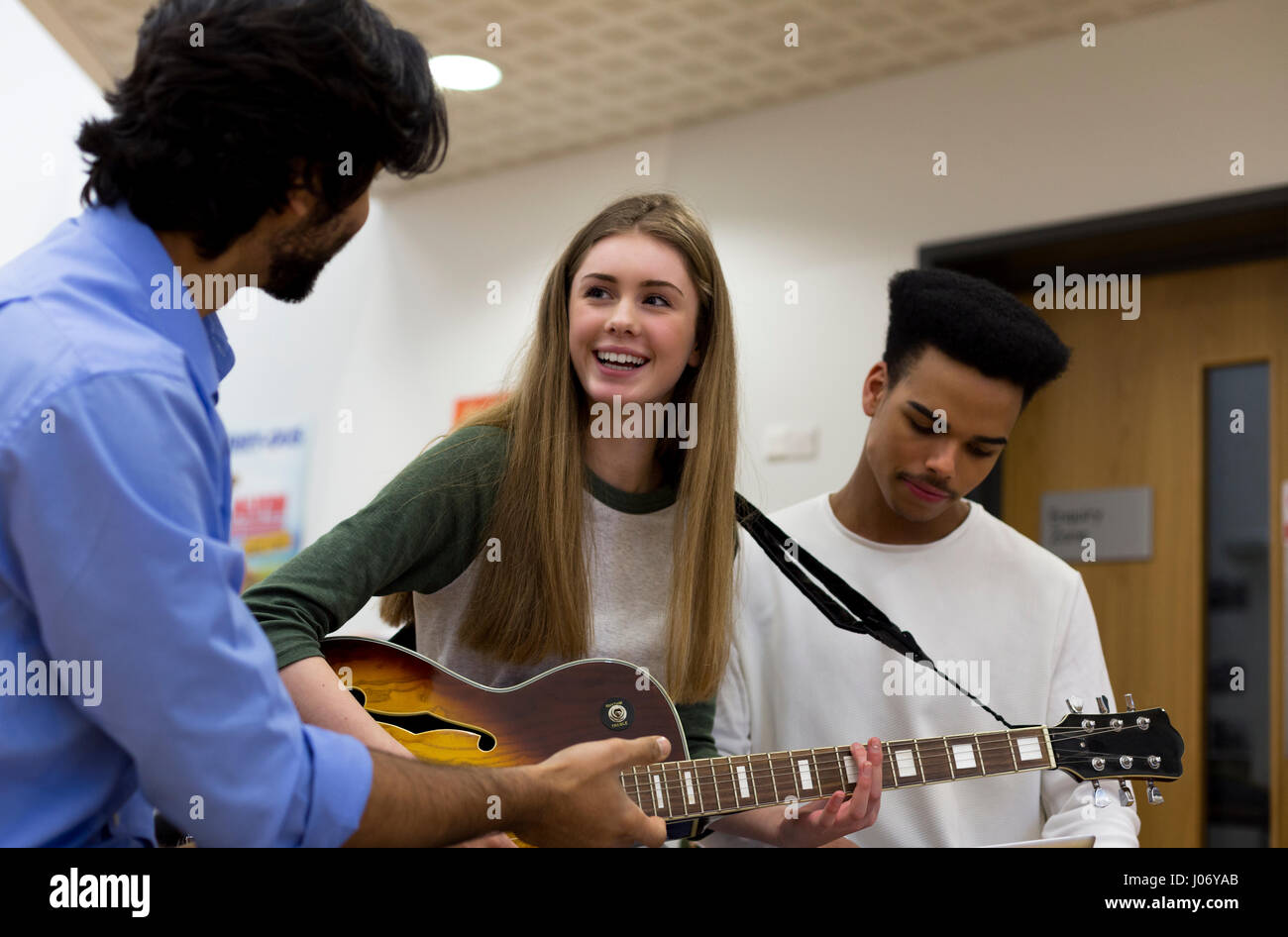 Musiklehrer, Unterstützung der Schüler lernen, Gitarre zu spielen. Stockfoto