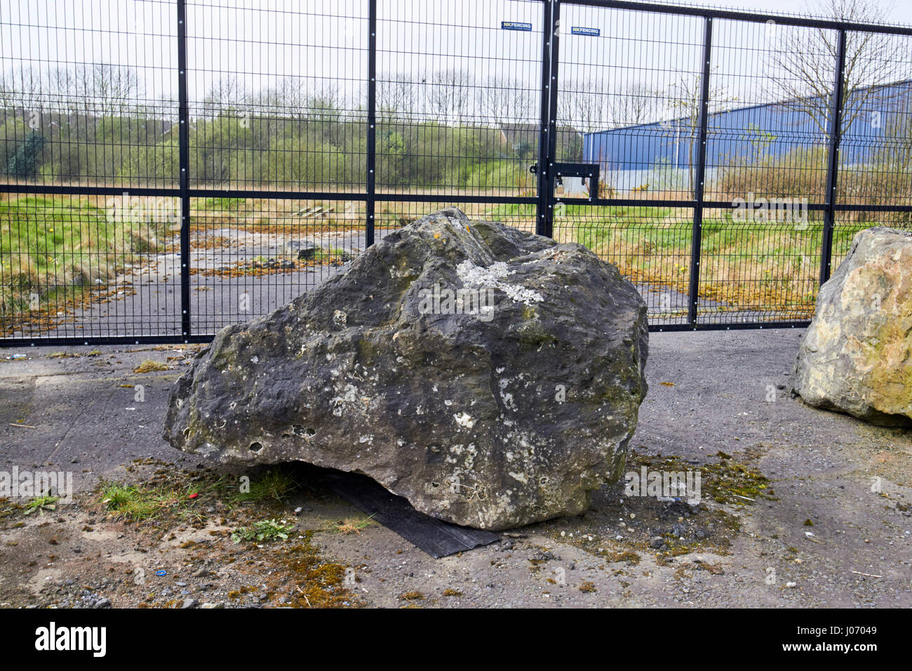 große Felsbrocken vor verfallenen kommerzielle Handlung gegen Reisende hocken vor Ort Newtownabbey UK platziert Stockfoto