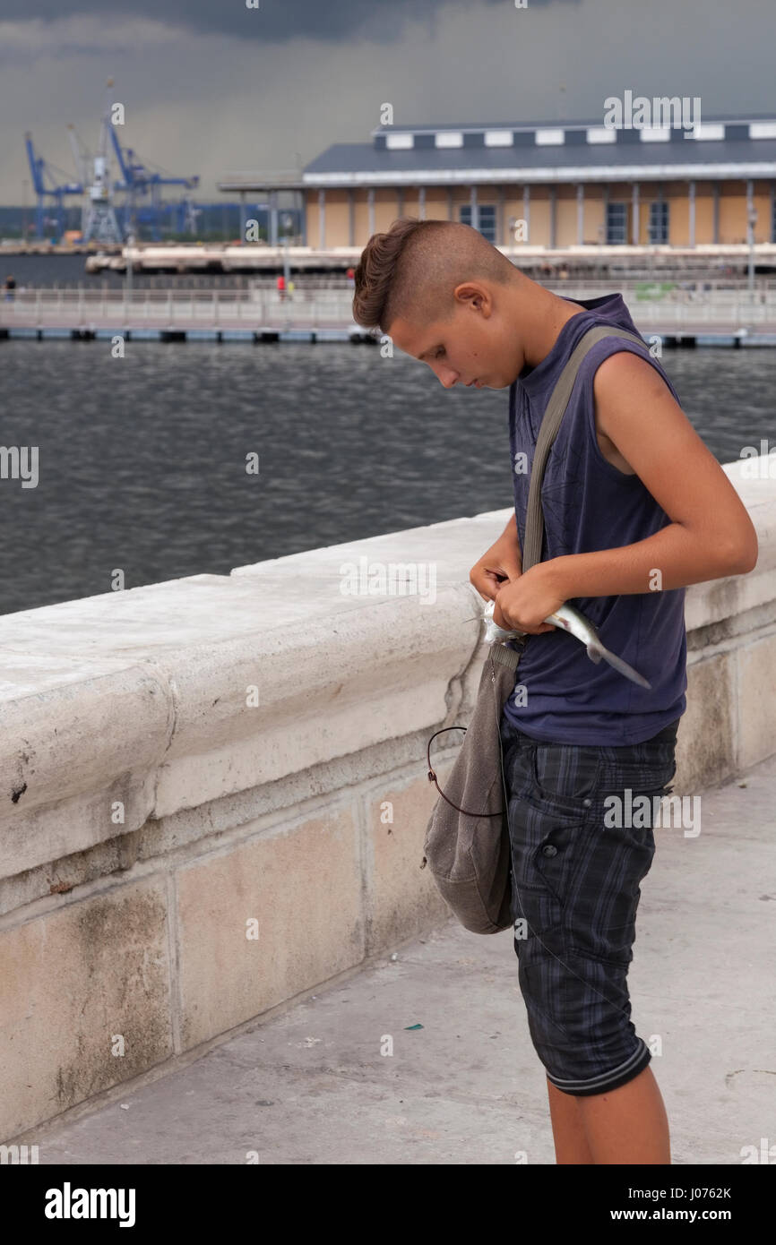 Eine junge kubanische entfernt einen Haken ein Fisch an der Uferpromenade entlang des Malecon in Alt-Havanna, Kuba. Stockfoto