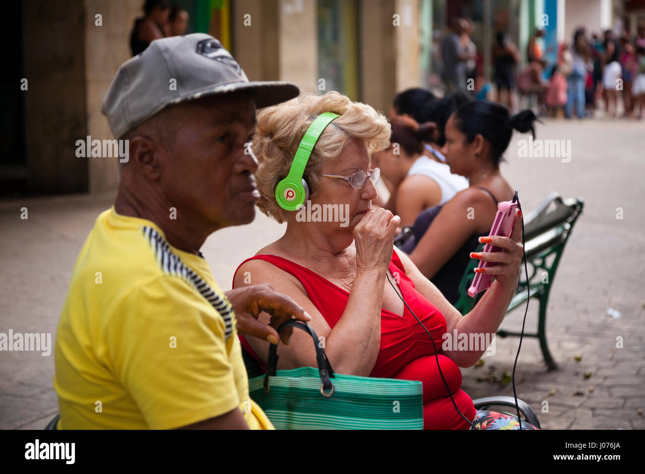 Eine kubanische Frau schaut ihr Smartphone mit Beats von Dre Kopfhörer in Alt-Havanna, Kuba. Stockfoto