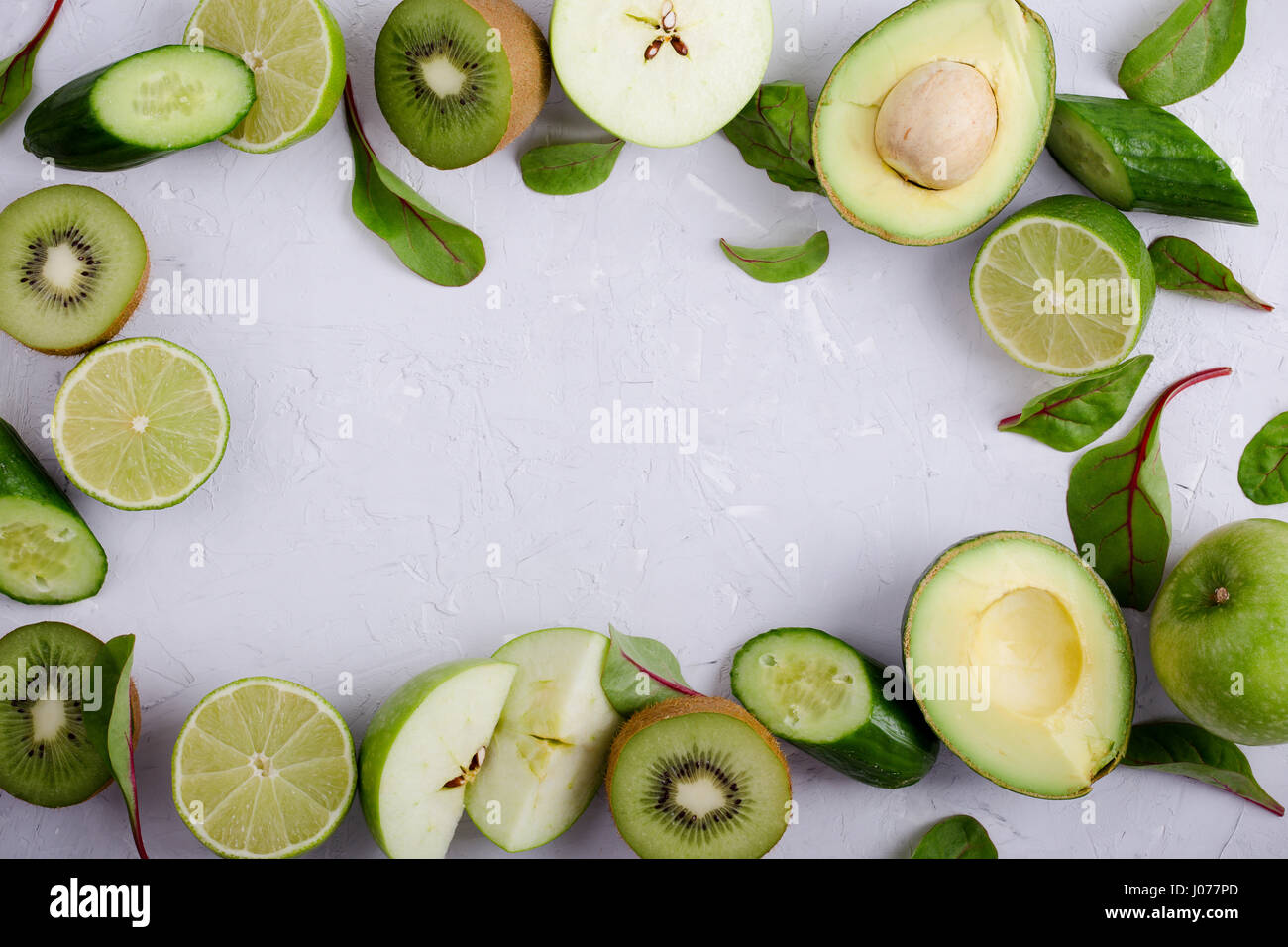 Rahmen von grünem Gemüse und Obst über leichte graue Putz Tisch, Essen Hintergrund mit freiem Speicherplatz für text Stockfoto