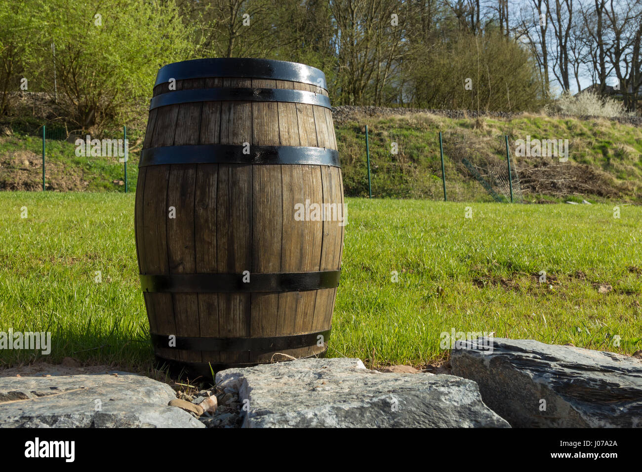 Fass auf der linken Seite mit einem grünen Rasen und Bäumen im Hintergrund Stockfoto