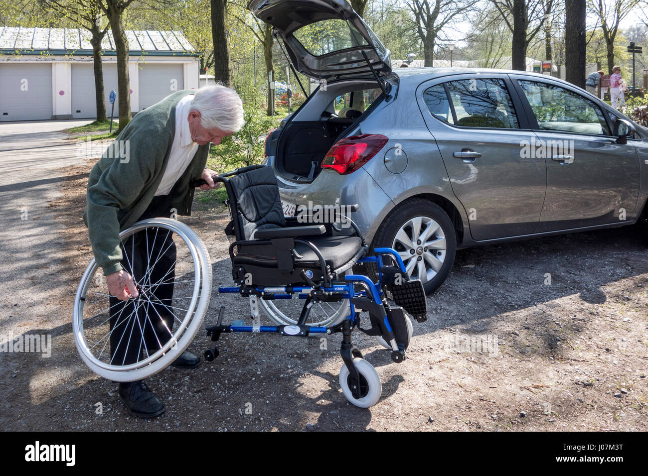 Senior woman Montage / Demontage Rollstuhl von körperlich behinderten älteren Frau vor Auto am Parkplatz Stockfoto