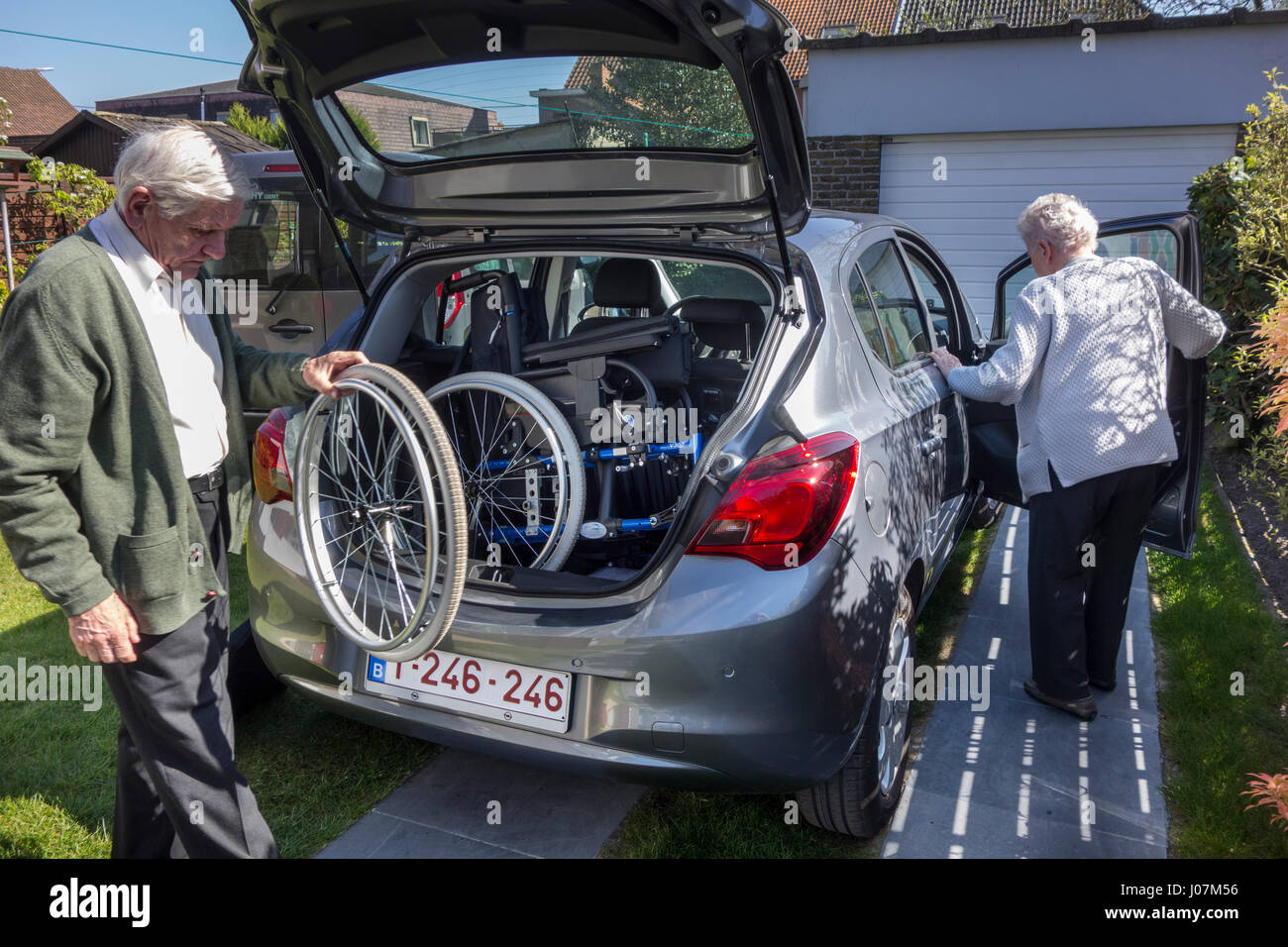 Ältere Mann Montage nicht demontiert Rollstuhl von körperlich behinderten älteren Frau im Kofferraum eines Autos zu Hause vor dem Schlafengehen für eine Fahrt Stockfoto