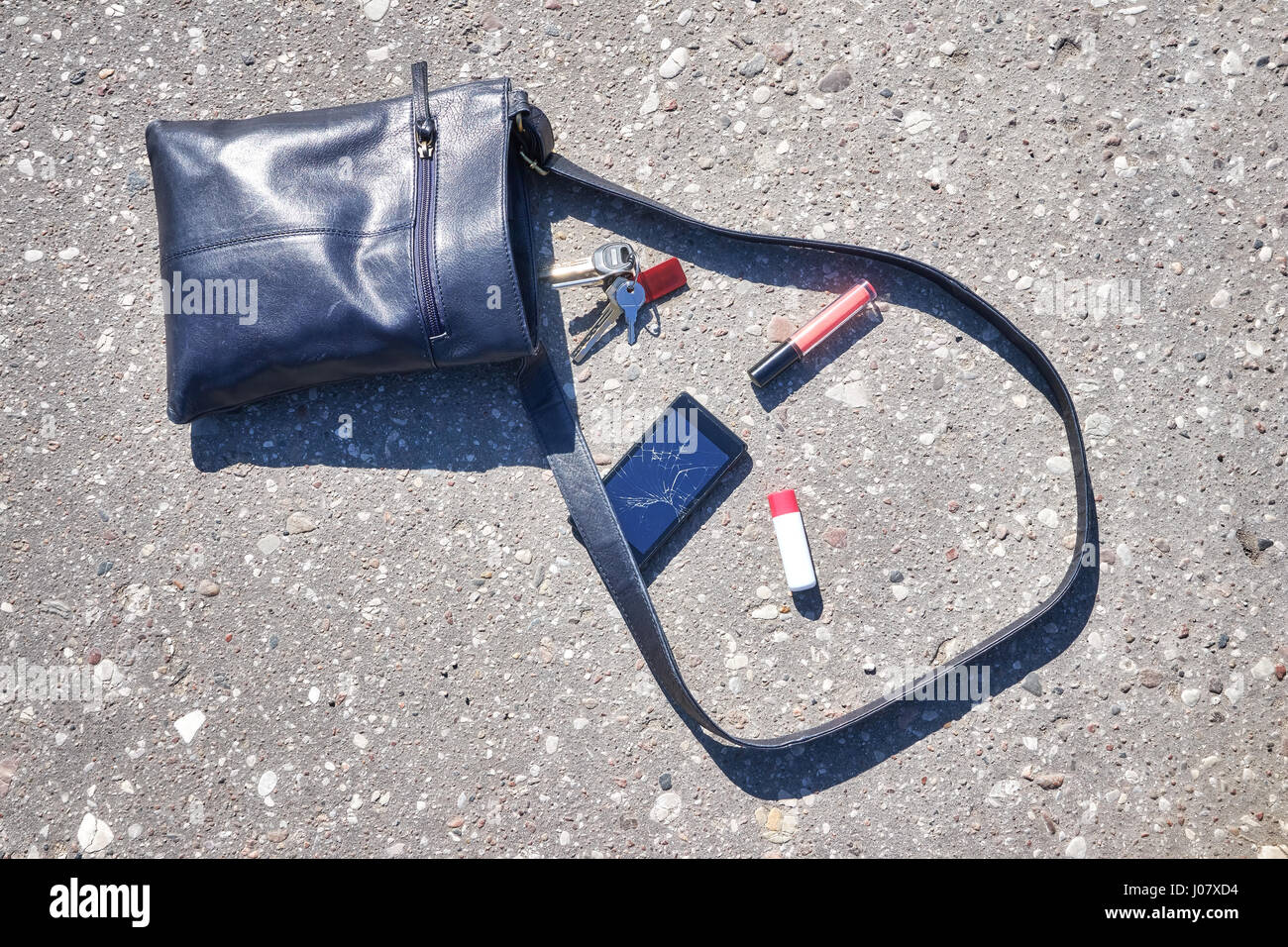 Handtasche, Handy mit zerbrochenen Bildschirm, Schlüsseln und Lippenstift auf Asphalt Straße, konzeptionelle Bild. Stockfoto