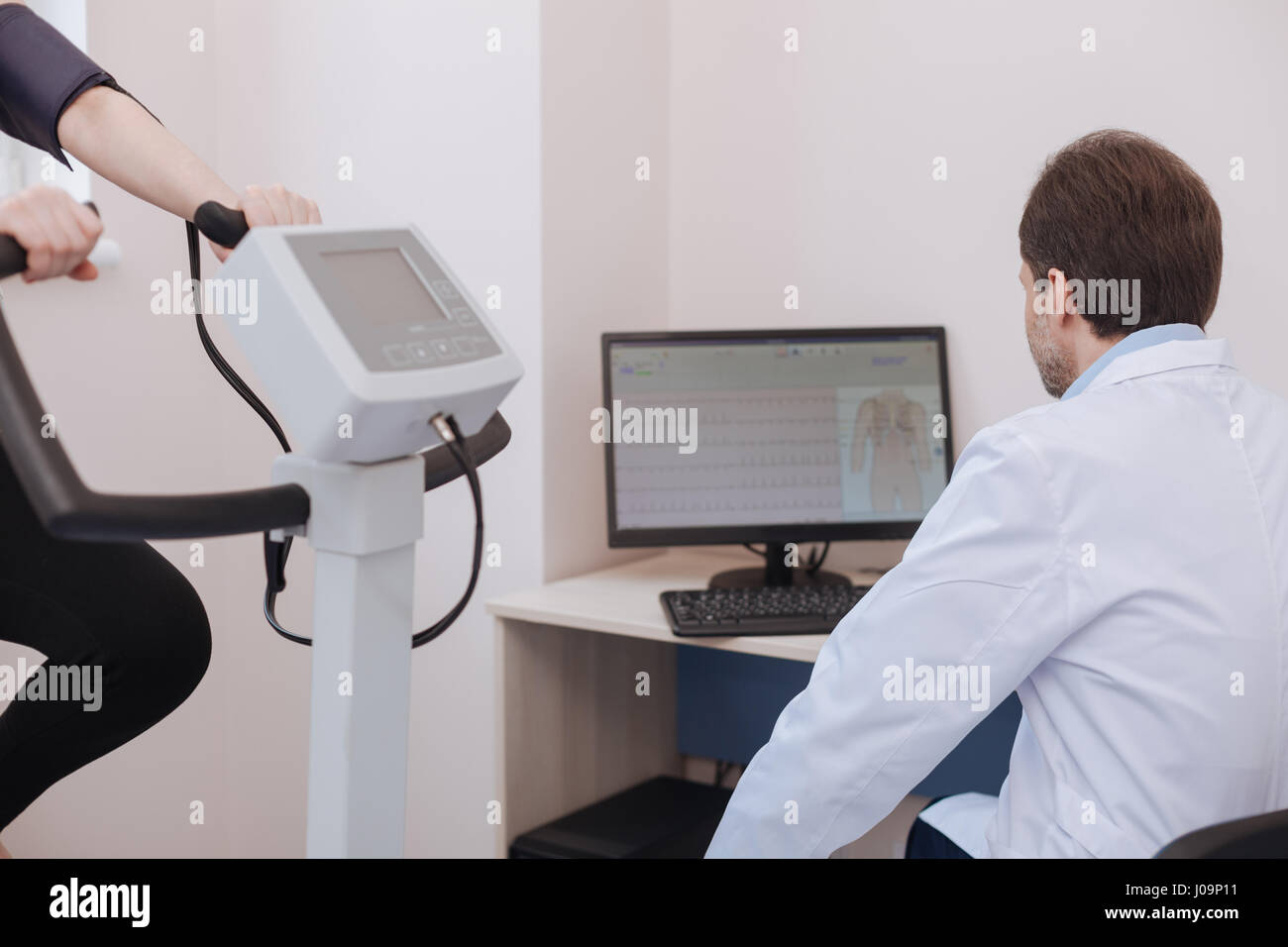 Der Einsatz moderner Technologien. Professionellen jungen Kardiologen mit seinem Computer Beobachtung vieler Patienten körperliche Leistungsfähigkeit und Mak gewidmet Stockfoto