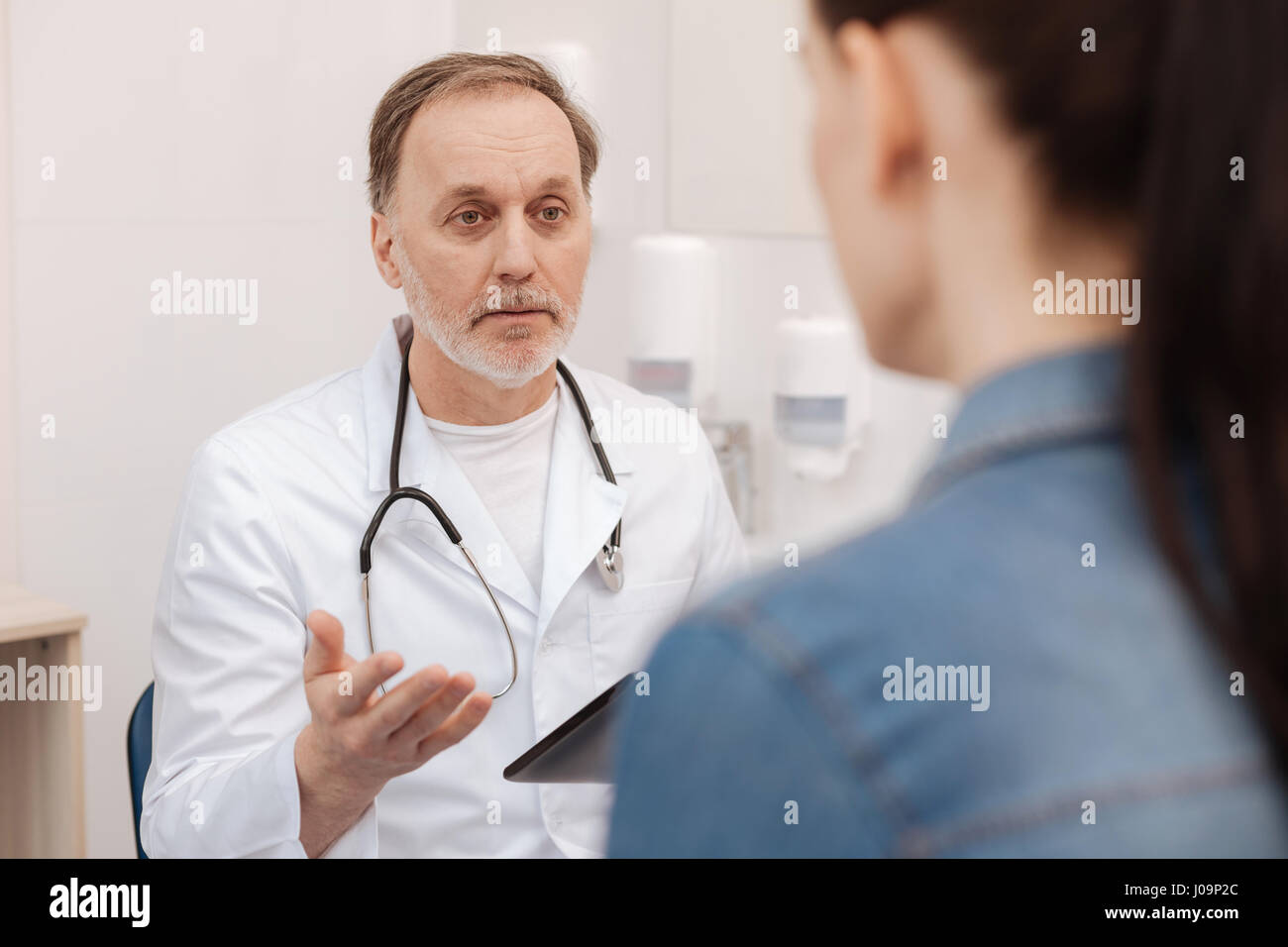 Reife zuständigen Arzt etwas mit seinem Patienten zu diskutieren Stockfoto