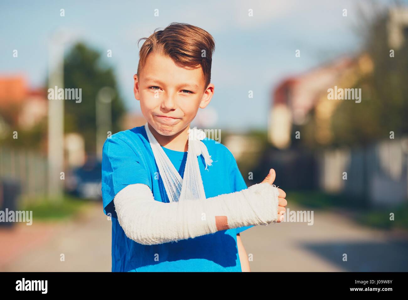 Schelmische Junge mit gebrochenen Hand verletzt nach Unfall OK Anzeichen Stockfoto