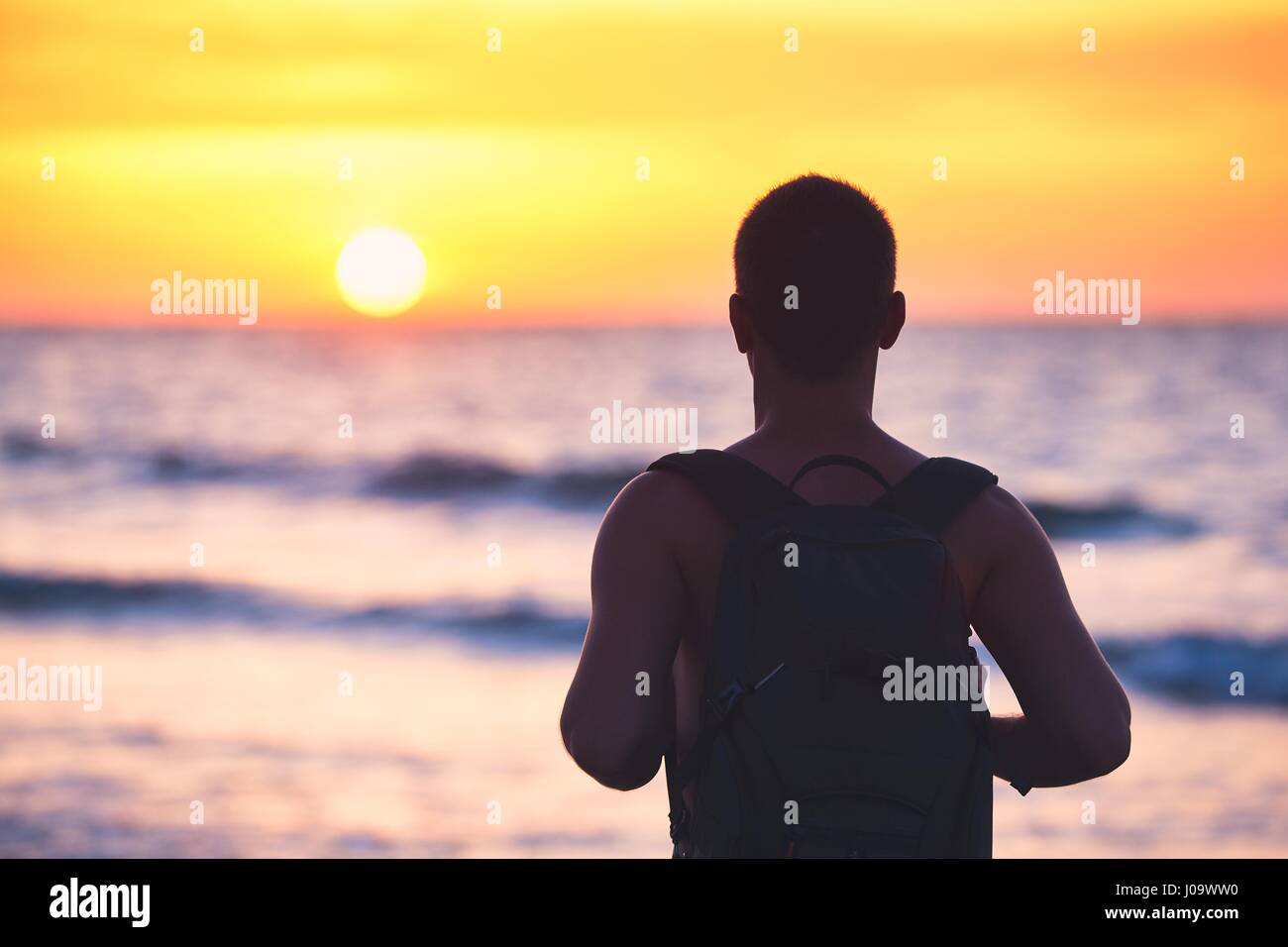 Junger Mann am Strand und idyllischen Sonnenuntergang genießen. Stockfoto