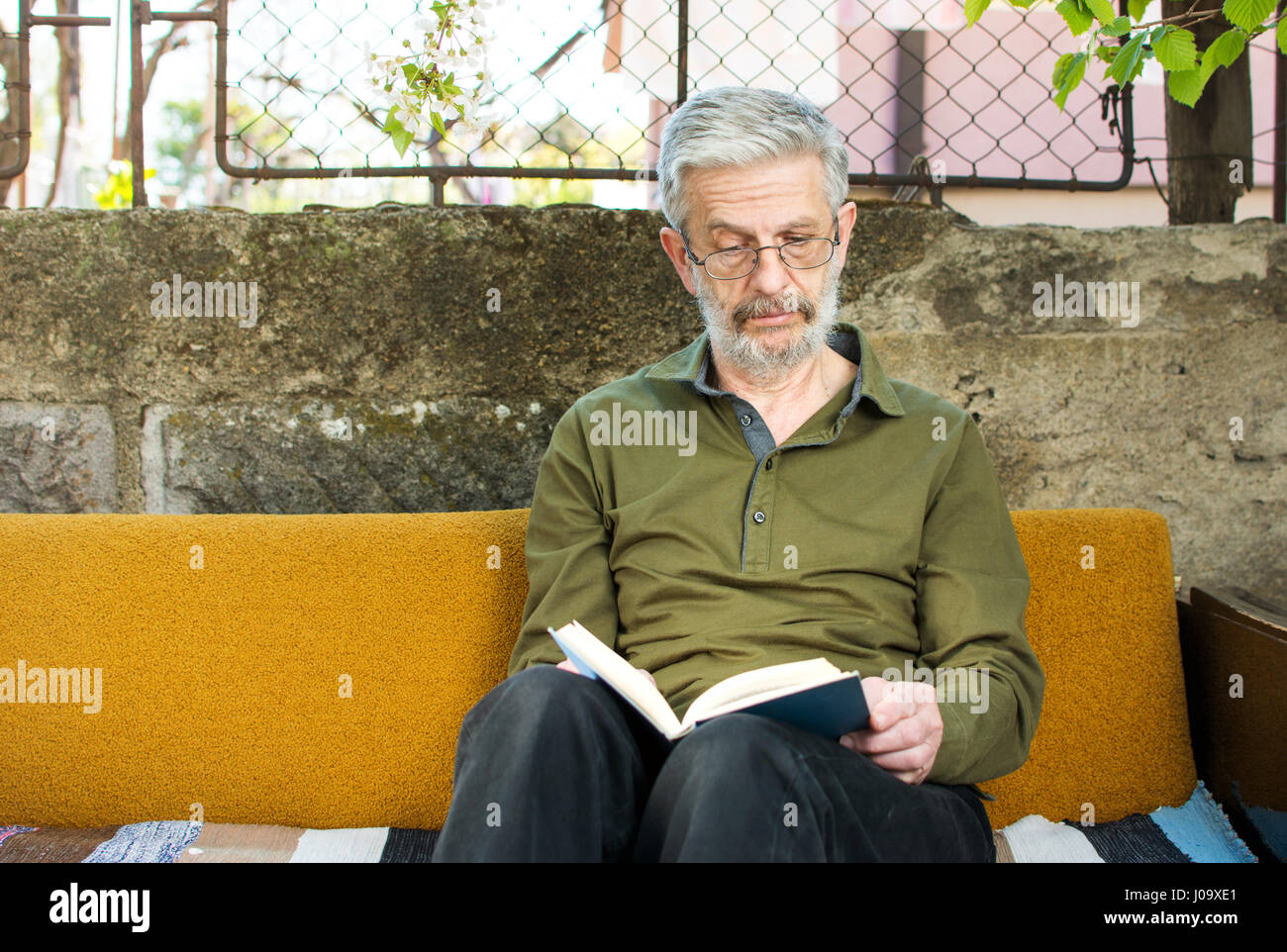 Mann liest ein Buch auf Schlafsofa im Hinterhof Stockfoto