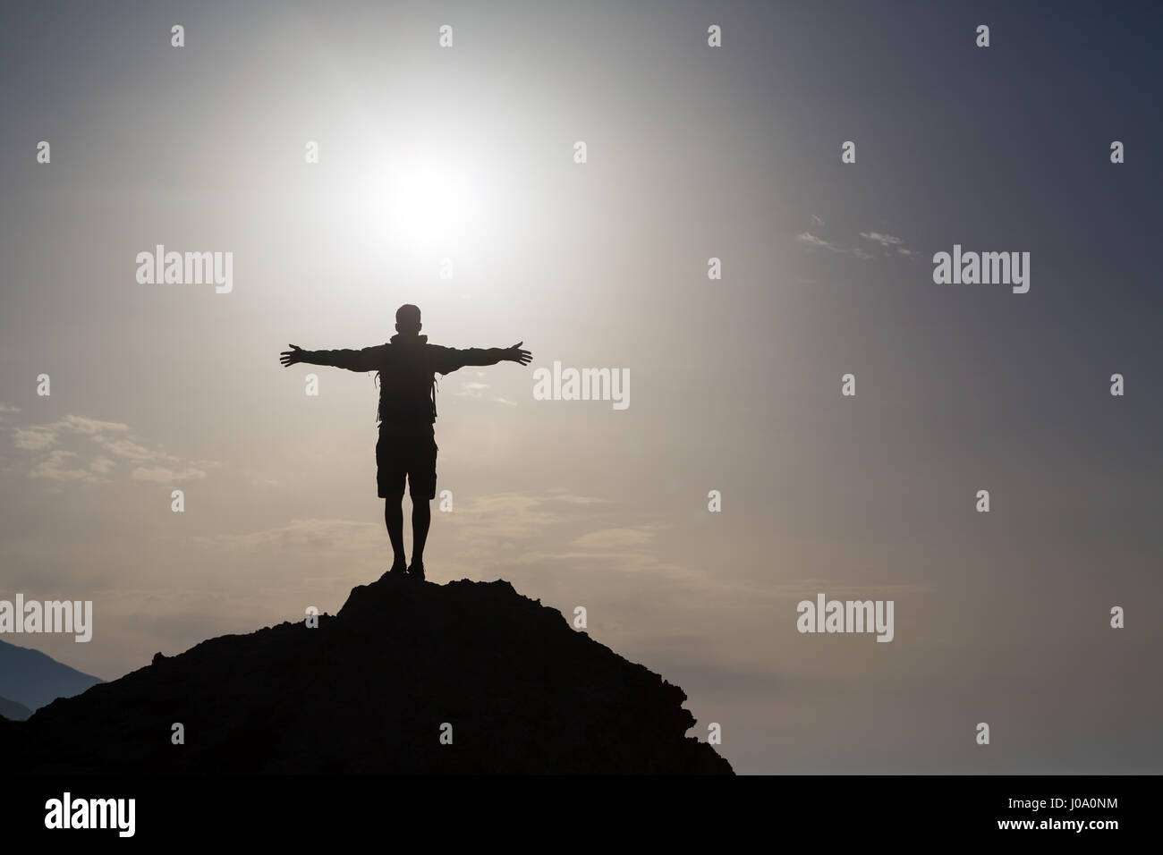 Mann mit ausgestreckten Armen zu feiern oder in schönen inspirierenden Berge Sonnenaufgang beten, silhouette. Mann, Wandern oder Klettern mit Händen oben genießen ins Stockfoto