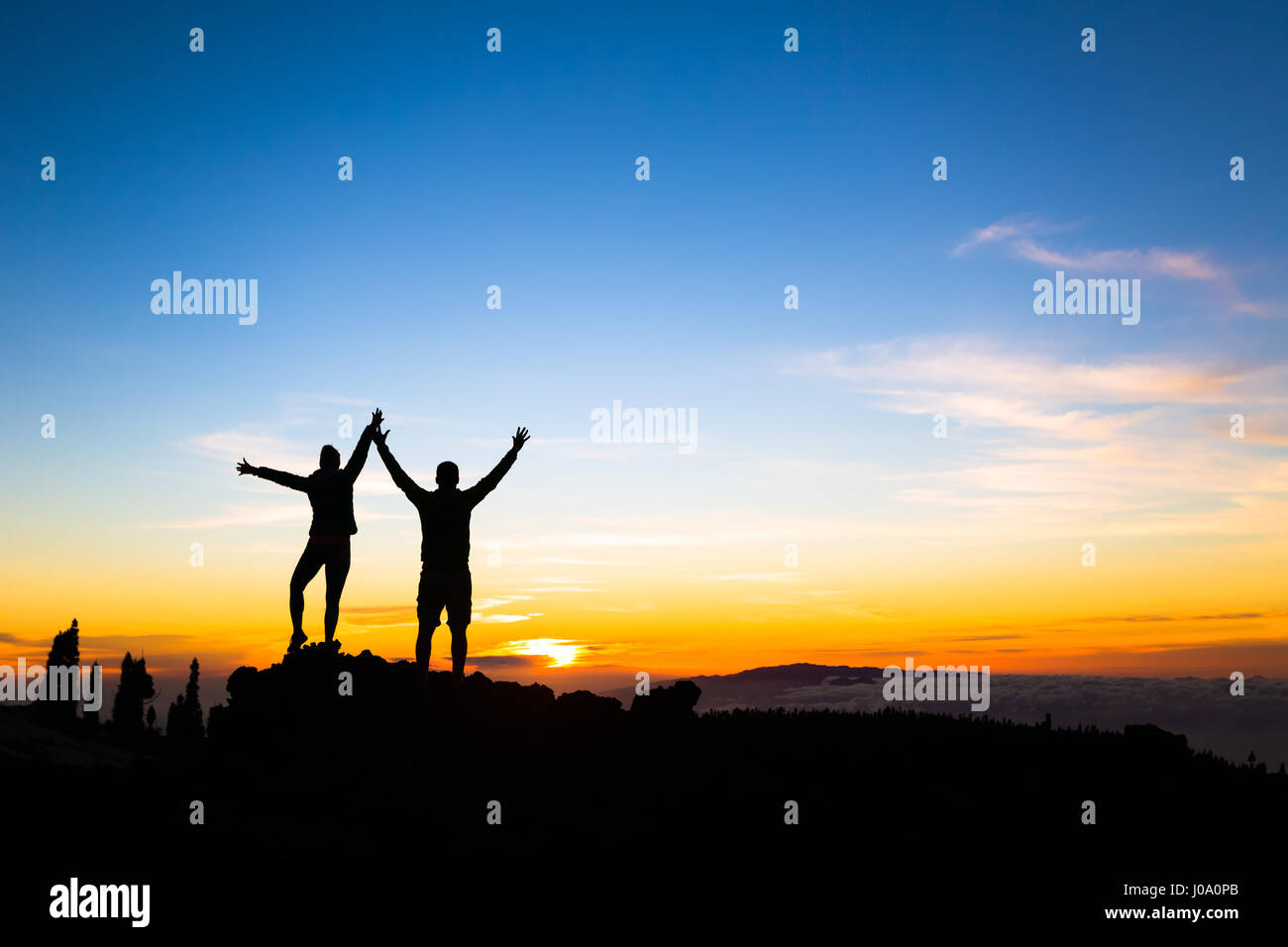 Paar Wanderer Erfolg im Sonnenuntergang Gebirge, mit ausgestreckten Armen erreicht. Mann und Frau auf felsigen Berg Blick auf schönen Sonnenuntergang inspira Stockfoto