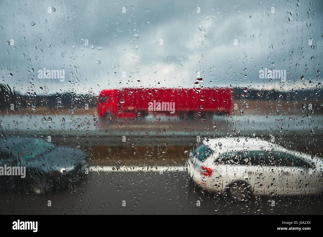 Nahaufnahme auf die Regentropfen. Verkehr auf der Autobahn bei Regen. Stockfoto