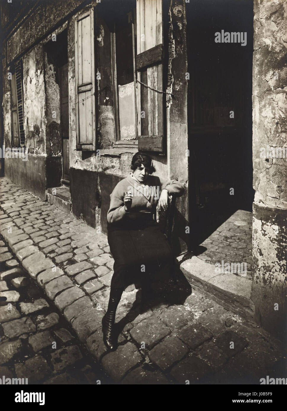 Eugène Atgets Fotografie „La Villette fille publique faisant le quart“ aus dem Jahr 1921 zeigt eine Frau im Pariser Stadtteil La Villette und spiegelt Atgets Fokus auf die Dokumentation des städtischen Lebens wider. Stockfoto