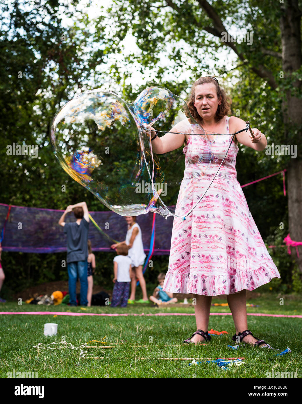 Frau, die Blase, die Kinder in einem Sommer-Festival-Workshop zu demonstrieren Stockfoto