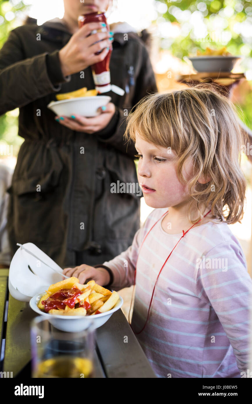 Kind eine Schüssel essen chips mit Ketchup in einem Gastgarten Stockfoto