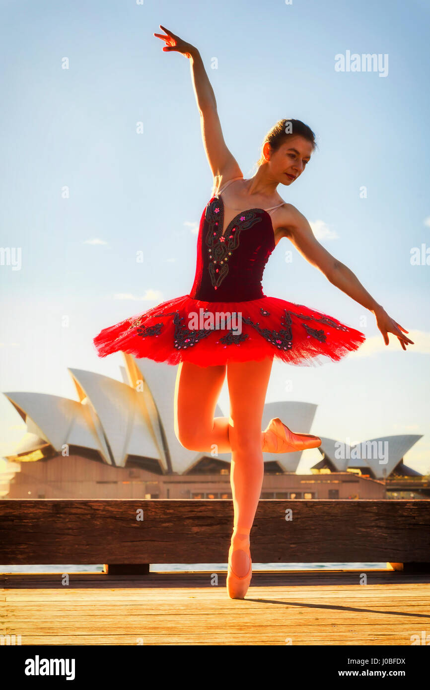 Jungen Ballerina in rot passen Konzert Tutu Dehnung unter Punkt Schuhe unter Punkt Position im Freien auf der Straße in Sydney im warmen Licht der aufgehenden Sonne wieder Stockfoto