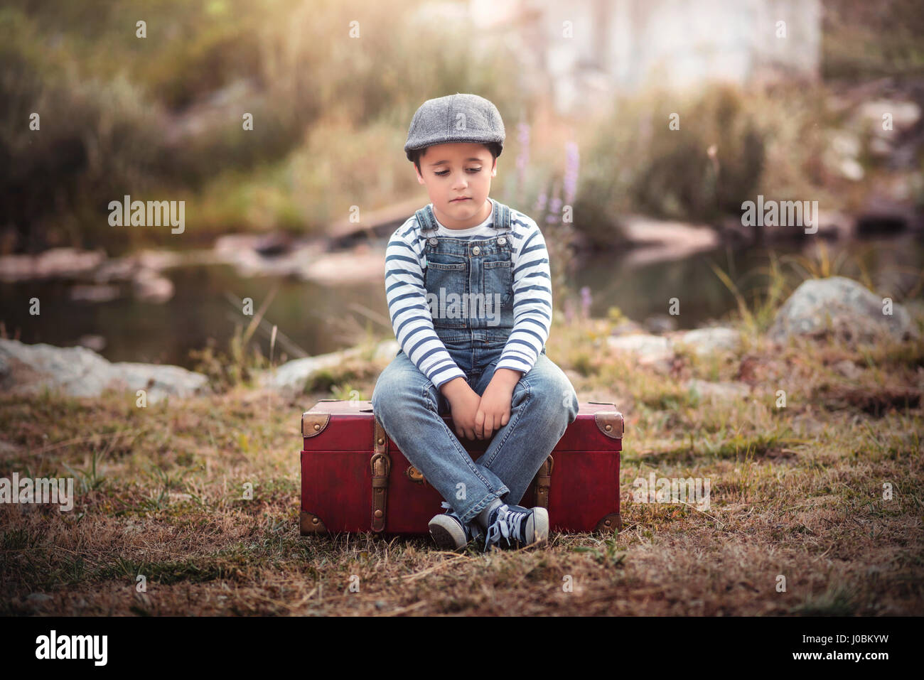 Trauriges Kind sitzt in einem Koffer Stockfoto