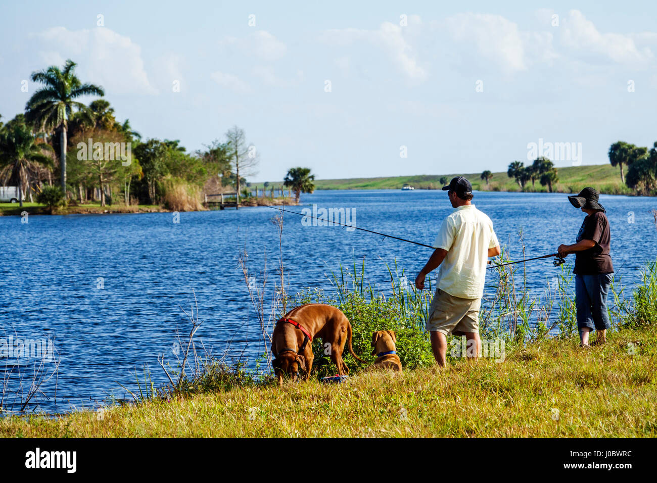 Florida Lake Okeechobee, Kanal, malerische Strecke, Park, Weg, Erwachsene Erwachsene Mann Männer männlich, Frau Frauen weibliche Dame, Hund Hunde, Angeln, am Wasser, Besucher Reisen tra Stockfoto