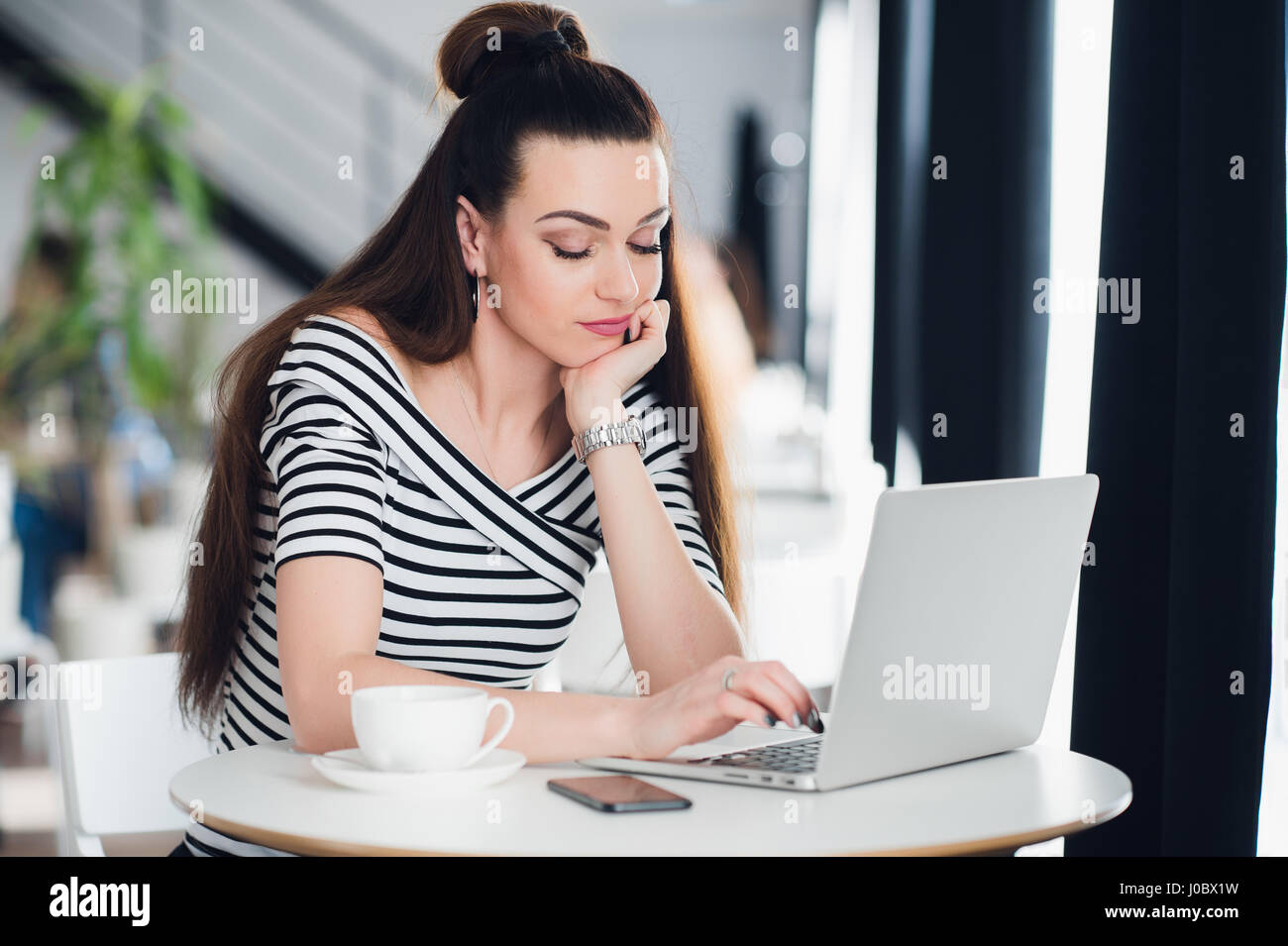 Gelangweilte Frau Surfen im Internet in einem Café bei einer Tasse Kaffee. Stockfoto
