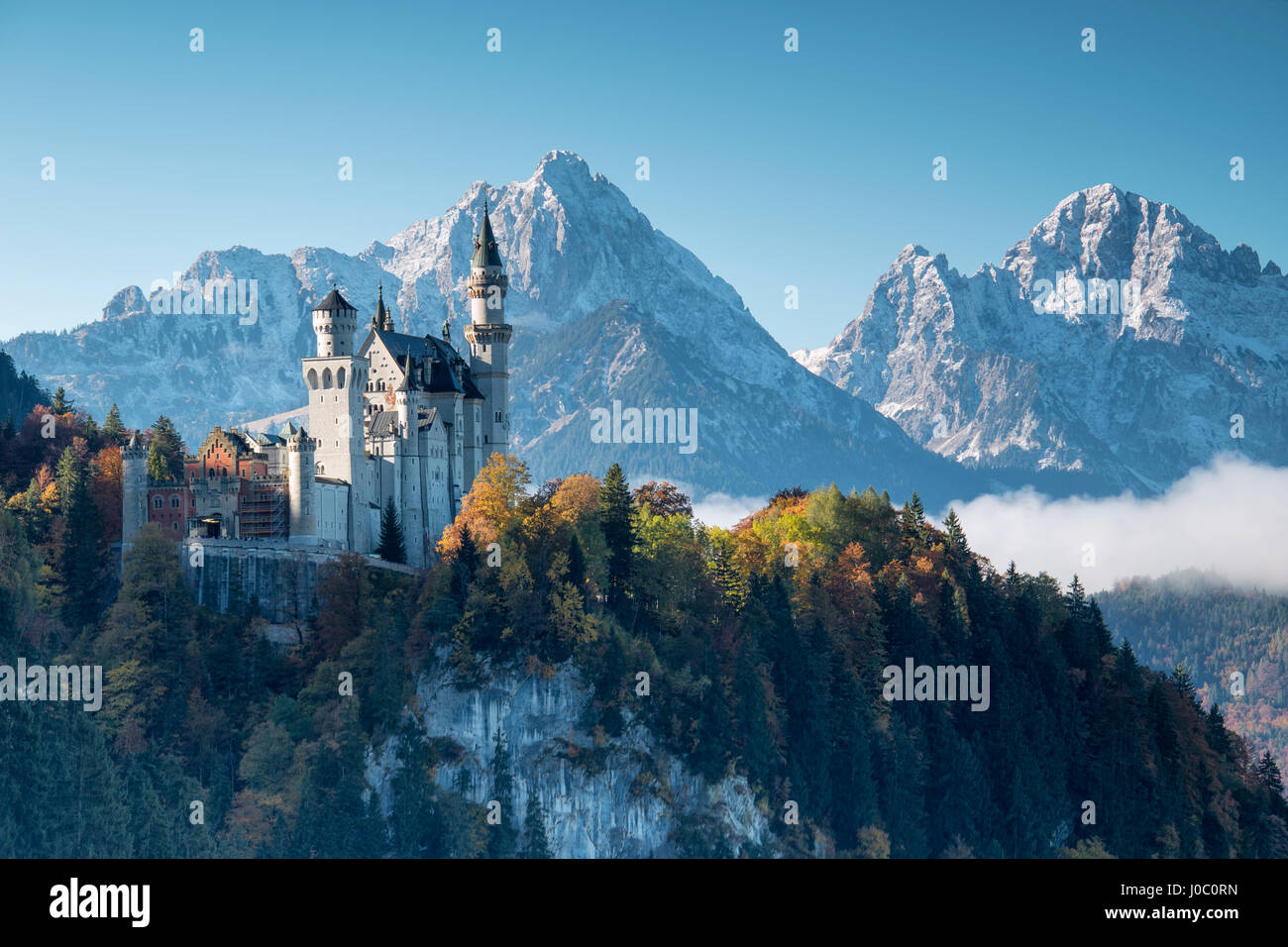 Schloss Neuschwanstein, umgeben von bunten Wäldern und schneebedeckten Gipfeln, Füssen, Bayern, Deutschland Stockfoto