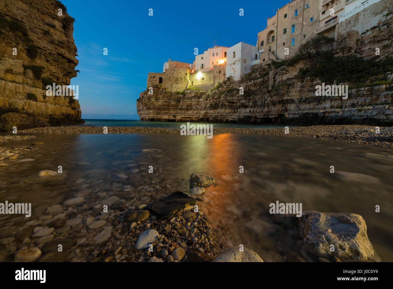 Dämmerung Licht auf das klare Meer, eingerahmt von der Altstadt thront auf den Felsen, Polignano a Mare, Provinz Bari, Apulien, Italien Stockfoto