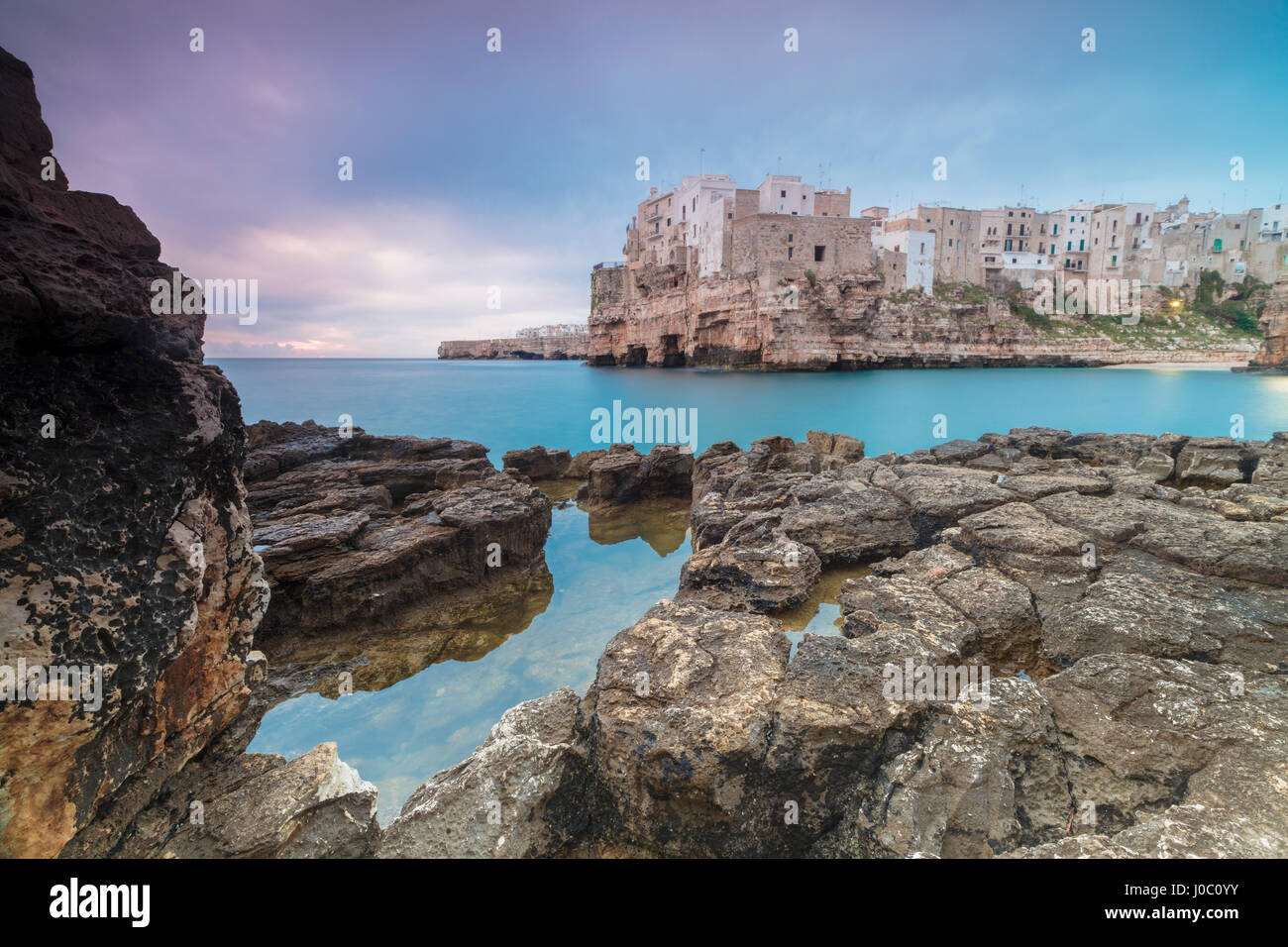 Türkisfarbenes Meer bei Sonnenaufgang, umrahmt von der Altstadt thront auf den Felsen, Polignano a Mare, Provinz Bari, Apulien, Italien Stockfoto