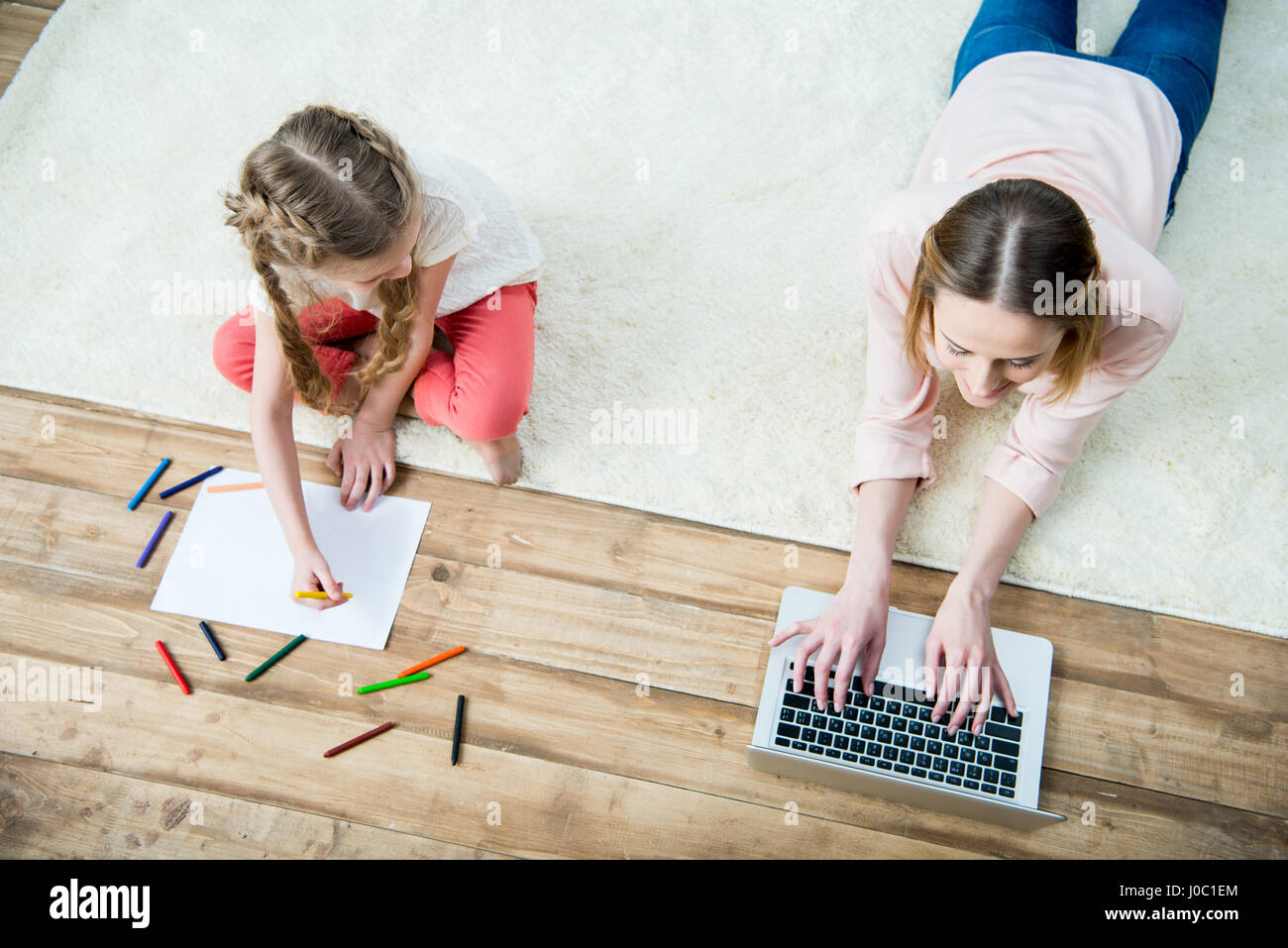 Draufsicht der lächelnde Mutter Surfen während Tochter Zeichnung Bild Stockfoto