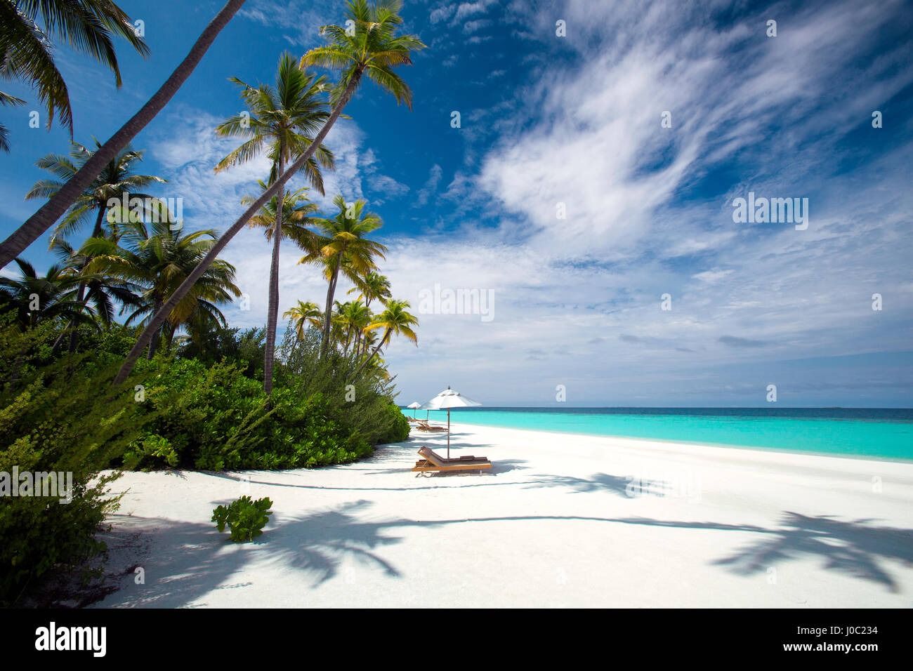 Liegestühle im Schatten der Sonnenschirm am tropischen Strand, Malediven, Indischer Ozean, Asien Stockfoto
