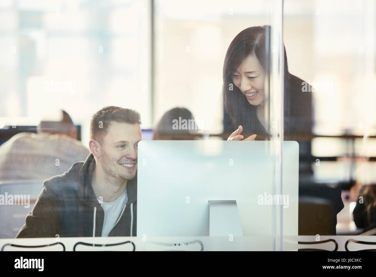 Studenten, die Arbeiten am Computer hinter Glaswand Stockfoto