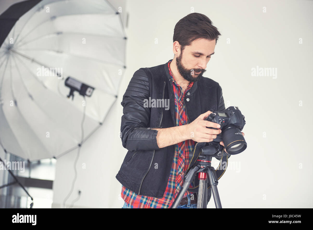 Männlichen Fotografen Überprüfung Studio Fotoshooting auf digitale slr Stockfoto