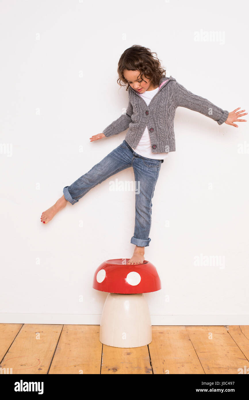 Junges Mädchen balancieren auf Fliegenpilz, Studio gedreht Stockfoto