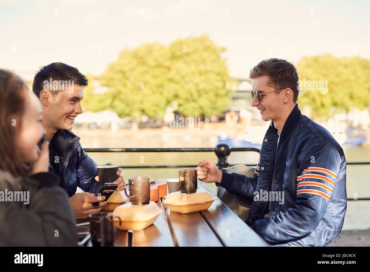 Drei Freunde, draußen sitzen, trinken heiße Getränke, Bristol, UK Stockfoto
