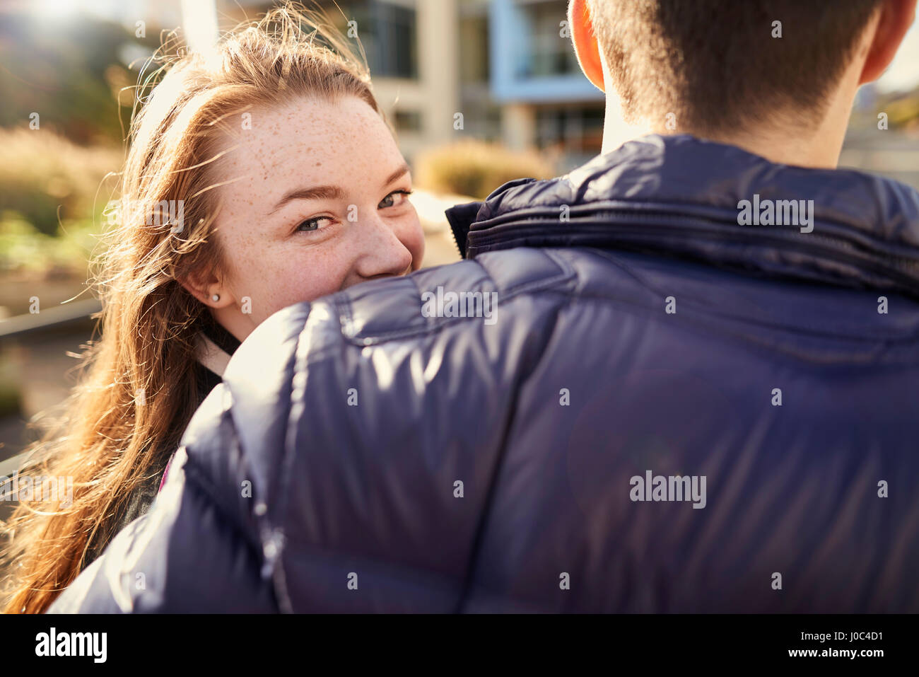 Zwei Freunde gehen im Freien, junge Frau auf der Suche über die Schulter, hintere Ansicht, Bristol, UK Stockfoto