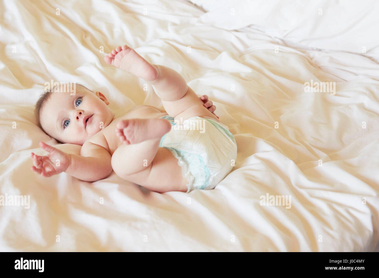 Porträt von niedlichen blauen Augen Babymädchen in Windel auf Bett liegend Stockfoto